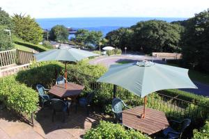 two tables and chairs with umbrellas on a patio at The Collingdale Guest House in Ilfracombe