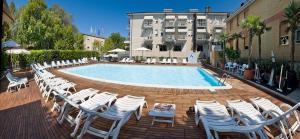 a pool with white chairs and a bunch ofitures at Hotel St. Moritz in Bellaria-Igea Marina