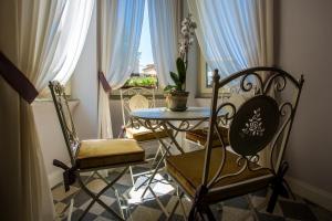 ローマにあるトラステヴェレ ロイヤル スイートのテーブルと椅子2脚、窓が備わる客室です。