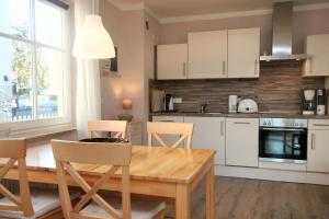 a kitchen with a wooden table and a kitchen with white cabinets at Villa Vogelsang by Rujana in Binz