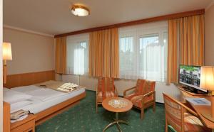 ein Hotelzimmer mit einem Bett, einem Tisch und Stühlen in der Unterkunft Hotel Hallerhof in Bad Hall