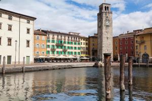 una torre de reloj junto a un río con edificios en Hotel Centrale, en Riva del Garda