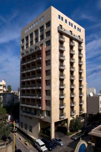 ein hohes Gebäude mit Autos auf einem Parkplatz in der Unterkunft ParkTower Suites in Beirut