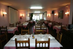 a dining room with tables with red and white tablecloths at Hotel Can Mestre in El Pont de Suert