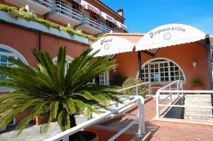a palm tree in front of a building with an umbrella at Hotel Acquamarina in Portoferraio