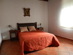 a bedroom with a bed with an orange bedspread at Alojamiento Rural La Rabida 25 in Cumbres Mayores