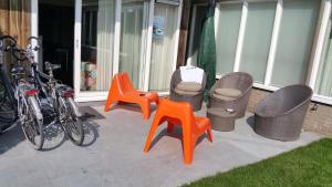 three orange chairs and wicker chairs on a patio at Comfort-Appartement ZEEDUIN, op Beg grond met Terras - volledige KEUKEN - Resort Amelander Kaap met gebruik van verwarmd Hotel-ZWEMBAD in Hollum