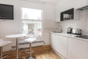 a kitchen with white cabinets and a window at Apartment near Harrods in London