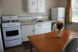 uma cozinha com uma mesa, um fogão branco e um frigorífico em Boundary Motel em Osoyoos