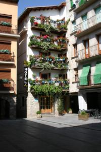 un edificio alto con balcones y plantas. en Hotel Can Mestre, en El Pont de Suert