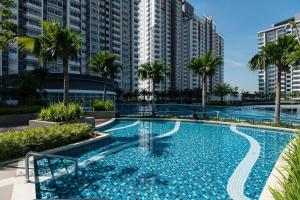 a large swimming pool with palm trees and buildings at Palm Armada Residence Free Parking and Netflix in Putrajaya