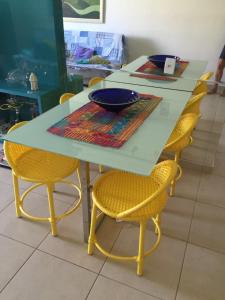 a table with yellow chairs and a blue bowl on it at Mediterrane Residence in Aquiraz