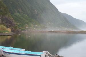 a boat sitting on the shore of a body of water at Casa da Lagoa AL 416 in Fajã da Caldeira de Santo Cristo
