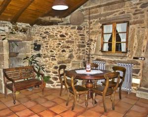 - une table et des chaises dans une pièce dotée d'un mur en pierre dans l'établissement Casa Refugio de Verdes, à Verdes