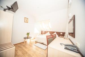 een kleine witte kamer met een bed en een bureau bij Hotel Ada in Większyce