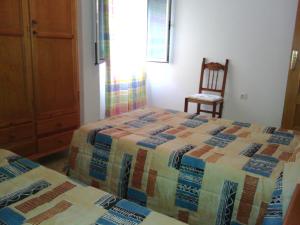 カルボネラスにあるApartamento Triniのベッドルーム1室(ベッド2台、木製椅子付)