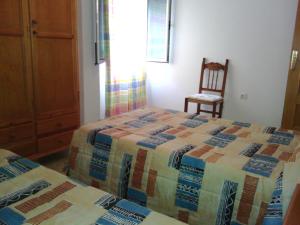 a bedroom with two beds and a wooden chair at Apartamento Trini in Carboneras