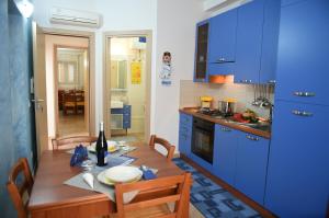 une cuisine avec une table en bois et des armoires bleues dans l'établissement Casa Vacanze Madrice, à Castellammare del Golfo