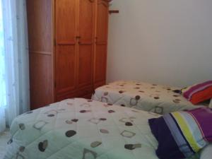 カルボネラスにあるApartamento Triniのベッドルーム1室(ベッド2台、木製キャビネット付)