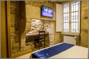 a bedroom with a bed and a tv on a stone wall at Oxford Suites Santiago de Compostela in Santiago de Compostela +33 photos