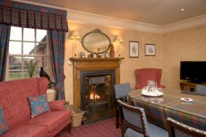 a living room with a table and a fireplace at Carfraemill in Lauder