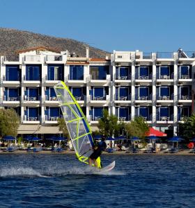 a person on a surfboard with a sail in the water at Trokadero Boutique Hotel in Itea