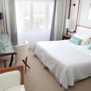 a bedroom with a bed and a desk and a window at Atlantic Hôtel & Spa in Les Sables-d'Olonne