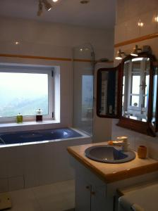 een badkamer met een wastafel, een bad en een raam bij indé no in Sari Solenzara