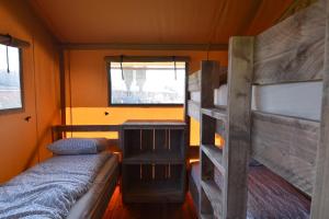 een kleine kamer met 2 stapelbedden en een raam bij Glamping Aan de Vleterbeke in Oostvleteren