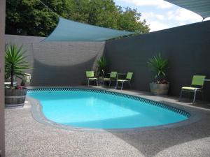 a large swimming pool with chairs and a fence at Rotorua Motel in Rotorua