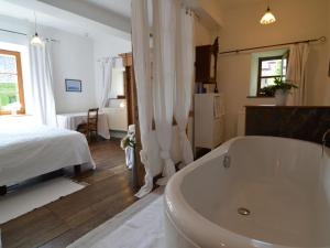 a bathroom with a tub and a bed and a bedroom at Enchanting Cottage with Terrace Garden in Hamoir