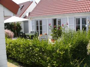 デ・ハーンにあるPleasant Holiday Home in De Haan by the Seaの赤い屋根と茂みのある白い家