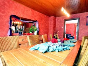 ビュートゲンバッハにあるCosy Holiday Home with Sauna Terrace Garden BBQの赤い壁のダイニングルーム(木製テーブル付)