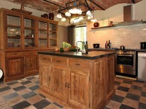 uma cozinha com armários de madeira e uma bancada em Rural holiday home in former stables em Beernem