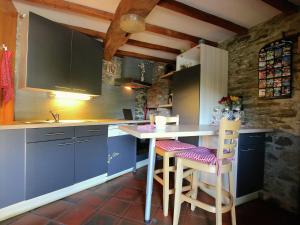 a kitchen with blue cabinets and two bar stools at Attractive Cottage in Baillamont with Terrace in Bièvre