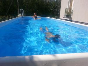 two people swimming in a blue swimming pool at Apartments with outdoor SPA jacuzzi and sauna in Vilnius