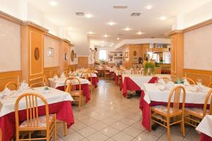 un restaurante con mesas con manteles rojos y blancos en Hotel Ambra, en Clusone