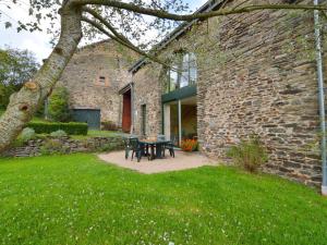 un edificio de piedra con una mesa y sillas en un patio en Comfortable Cottage in Neufmoulin with Meadow View, en Houffalize