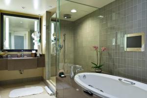 a bathroom with a tub and a sink and a mirror at Hotel Sofitel Los Angeles at Beverly Hills in Los Angeles