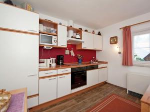 una cucina con armadietti bianchi e parete rossa di Apartment in the Pfaffenwinkel district a Prem