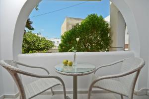 una mesa y sillas en un balcón con ventana en Margo Studios en Naxos