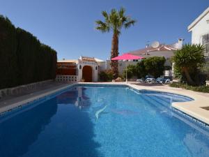 a swimming pool in front of a house with a palm tree at Belvilla by OYO Casa Fien in Rojales