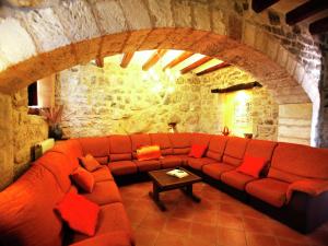 a living room with a red couch in a stone wall at Belvilla by OYO Cal Grapiss in Llacuna