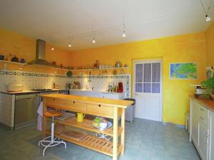uma cozinha com paredes amarelas e uma mesa de madeira em Charming holiday home with private pool em Cavaillon
