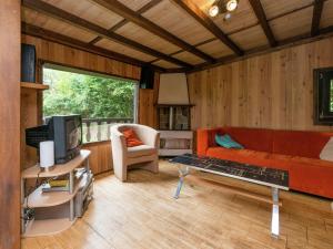 a living room with a couch and a tv at Sympathic Chalet not far from La Roche en Ardennes in La Roche-en-Ardenne