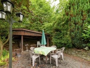 un tavolo con ombrellone e sedie verdi in cortile di Sympathic Chalet not far from La Roche en Ardennes a La-Roche-en-Ardenne