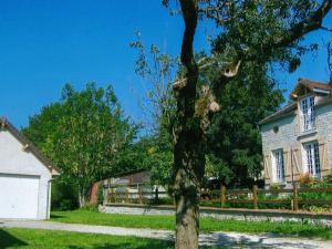 a tree in front of a house with a fence at Country cottage with enclosed garden in Bligny in Bligny
