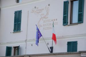 uma bandeira e um sinal na lateral de um edifício em Hotel La Fenice em Chiari