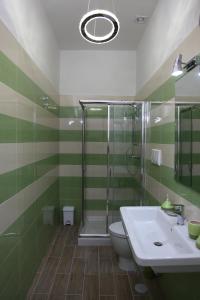 uma casa de banho verde e branca com um chuveiro e um lavatório em Blu d'aMare B&B em Porto Cesareo