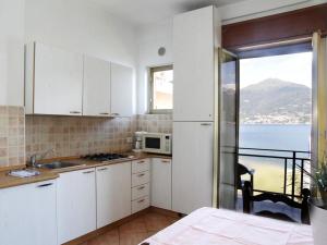 Spacious Apartment in Menaggio with Terrace في ميناجيو: مطبخ مع دواليب بيضاء واطلالة على الماء